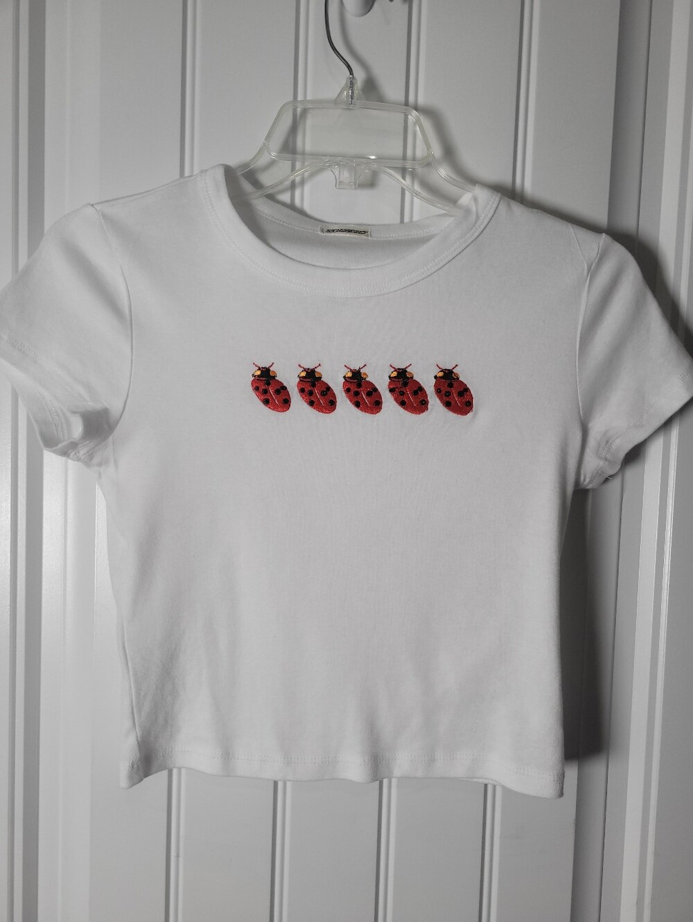 White Crop top baby tee features Red Ladybug Embroidery by Slubert.  Size S